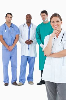 Smiling doctor with male staff members behind her against a white background