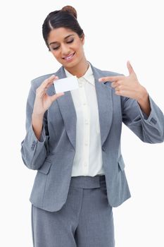 Smiling tradeswoman pointing at blank business card against a white background