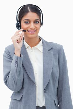 Smiling call center agent adjusting microphone against a white background