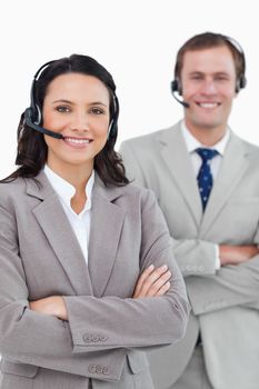 Smiling call center agents with headsets and arms folded against a white background