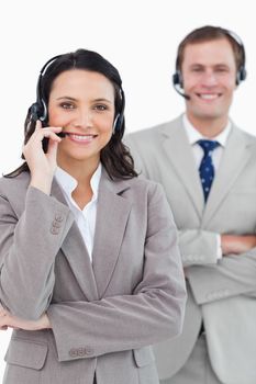 Smiling call center agents with headsets on and arms folded against a white background