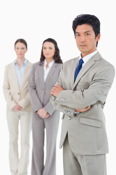 Confident looking businessman with his team behind him against a white background