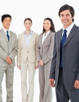 Smiling young salesman with his team behind him against a white background