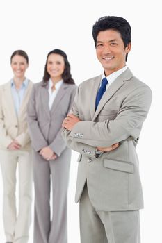 Confident smiling businessman with his employees behind him against a white background