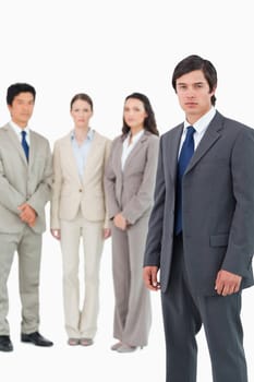 Serious young businessman with team behind him against a white background