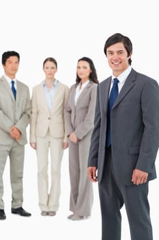 Smiling young salesman with team behind him against a white background