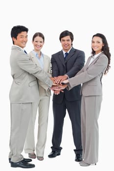 Smiling businessteam putting their hands together against a white background