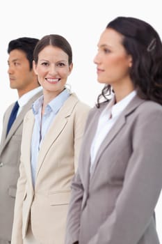 Smiling saleswoman standing between colleagues against a white background