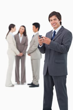 Smiling tradesman with cellphone and colleagues behind him against a white background