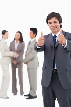 Salesman giving thumbs up with team behind him against a white background
