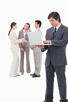 Salesman with laptop and team behind him against a white background