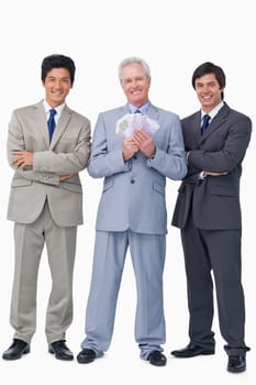 Smiling senior salesman with money and employees against a white background