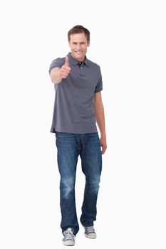 Smiling young man giving thumb up against a white background