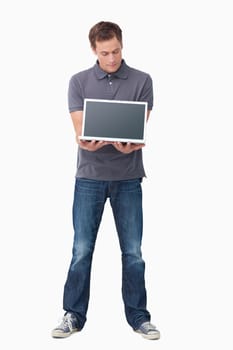 Young man showing screen of his laptop against a white background