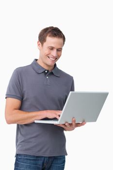 Smiling young man working on laptop against a white background