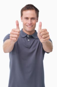 Thumbs up given by smiling young man against a white background