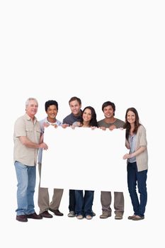 Smiling group of friends holding blank sign together against a white background