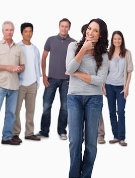 Woman in thinkers pose with friends behind her against a white background