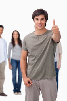 Smiling man giving thumb up with friends behind him against a white background