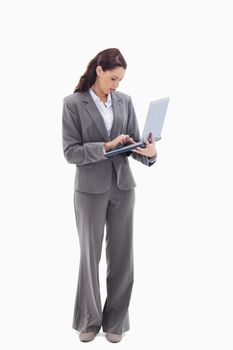 Businesswoman standing and typing on a laptop against white background