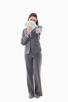Businesswoman approving and hiding with bank notes in her hand against white background