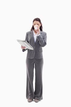 Businesswoman drinking a coffee and reading a newspaper against white background