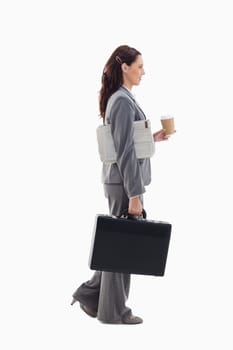 Profile of a businesswoman walking with a briefcase, with a newspaper under her arm and holding a coffee against white background