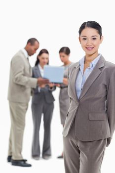 Businesswoman smiling with co-workers watching a laptop in the background against white background