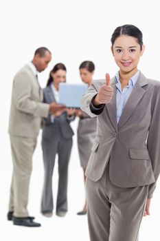 Businesswoman smiling and approving with co-workers watching a laptop in the background