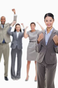 Close-up of a happy businesswoman clenching her fists with enthusiastic co-workers in the background