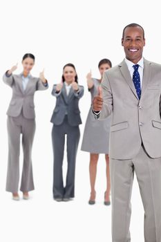 Business team smiling with thumbs up and with one businessman in foreground