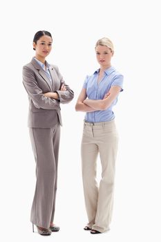 Two serious women crossing their arms against white background