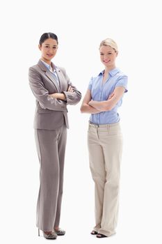 Two smiling women crossing their arms against white background