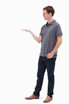 Standing man presenting and looking at his hand against white background