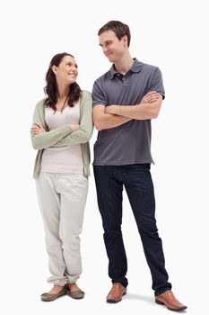 smiling couple looking at each other and crossing their arms against white background