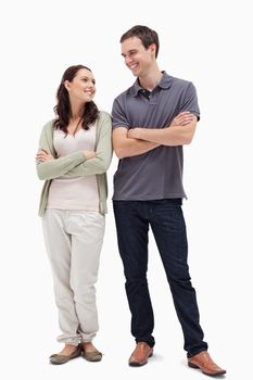 Couple with a complicit smile while crossing their arms against white background