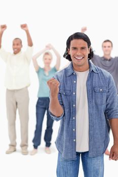 Big close-up of a man clenching his hand with people raising their arms in background