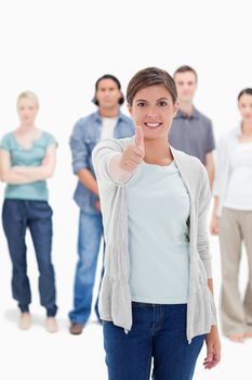 Close-up of a woman giving the thumb-up with people behind against white background
