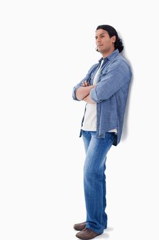 Man raising his eyebrow and leaning against a wall with white background