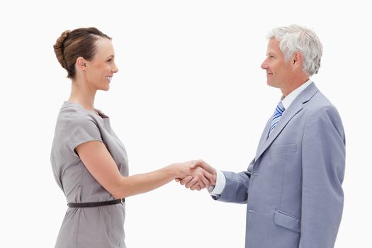 Close-up of a white hair man face to face and shaking hands with a woman against white background