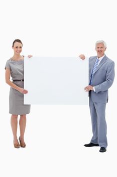 White hair businessman smiling and holding a big white sign with a woman against white background