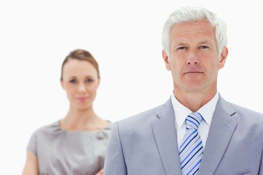 Close-up of a serious white hair businessman with a woman him behind against white background