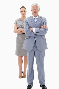 White hair businessman with a woman in background crossing their arms against white background