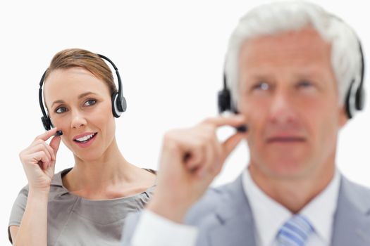 Woman in background man in front wearing a headset against white background