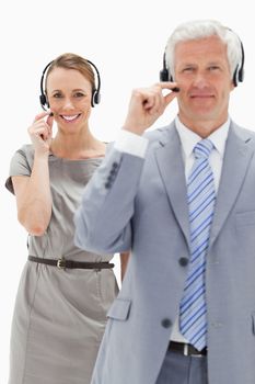 Close-up of a smiling woman in background and wearing a headset with a white hair man against white background