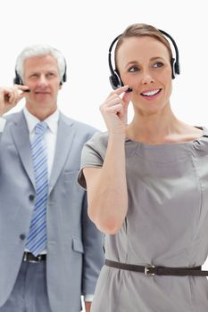 Close-up of a woman wearing a headset with a white hair businessman in the background