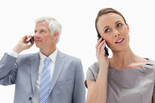 Close-up of a woman on the phone with a white hair businessman in background