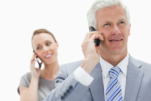 Close-up of a white hair businessman talking on the phone with a smiling woman in background