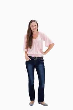 Woman smiling with her hand on the hip and the other hand in her pocket against white background
