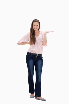 Young woman presenting with her hand on her hip against white background